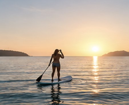 Paddleboarder on calm water at sunset