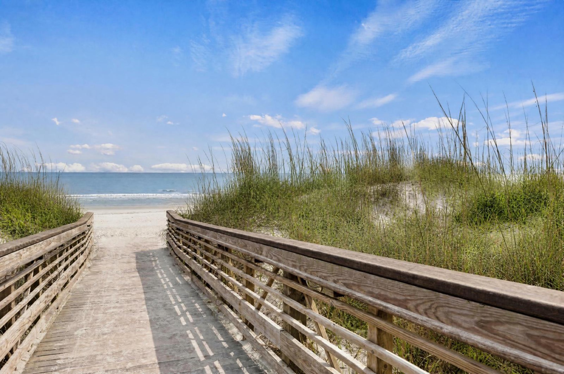 Wooden boardwalk through sea oats leading to the Atlantic